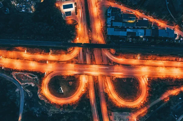 Aerial view of transport junction, asphalt city roads and Interchanges, top view from drone of circle motorways with bridges and car traffic at night — Stock Photo, Image