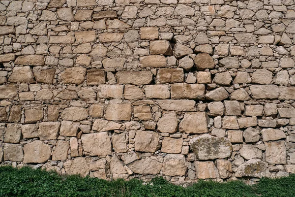 Tekstur dinding batu tua dengan rumput hijau, blok-blok permukaan puri kuno sebagai latar belakang desain — Stok Foto