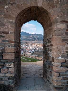 Küçük kasaba ve dağlarda manzaralı antik ortaçağ taş kale duvarında Kemer kapı