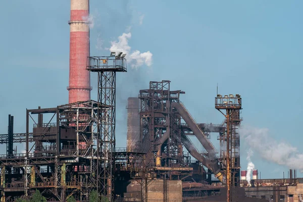 Iron tower constructions and pipes with smog of metallurgical plant as industrial background. Pollution from heavy industry