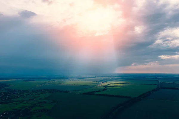 Schöne Luftpanoramalandschaft mit grünen Sommerwiesen, regnerischen Wolken und Sonnenstrahlen bei Sonnenuntergang, Drohnenbild — Stockfoto