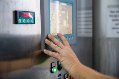 İşçi, içecek fabrikası veya fabrika endüstriyel ekipmanlarının kontrol paneline dokunuyor