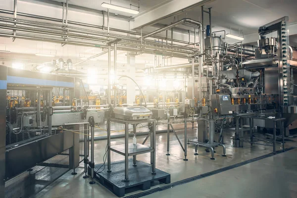 Förderband oder Linie in Getränkeindustrie mit moderner automatisierter industrieller Maschinenausrüstung. Plastikflaschen mit frischem Bio-Saft im Fabrikinneren — Stockfoto