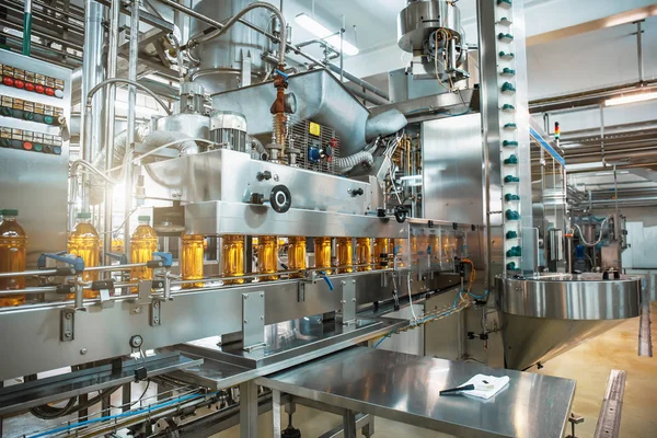 Cinta transportadora o línea en planta de bebidas con modernos equipos de máquinas industriales automatizadas. Botellas de plástico PET con jugo orgánico fresco en el interior de la fábrica — Foto de Stock