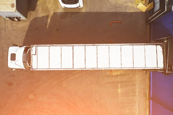 Letecká fotografie nákladních vozů v průmyslovém skladu nebo logistickém centru, čekající na nakládku zboží při osvětlení slunce, pohled shora — Stock fotografie