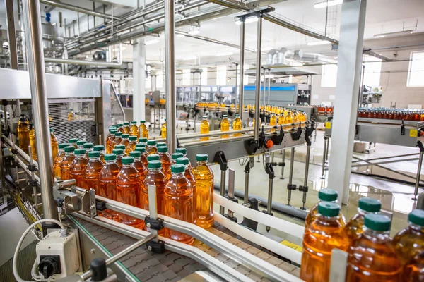 Sabuk pembawa atau garis di pabrik minuman dengan peralatan mesin industri otomatis modern. Botol PET plastik dengan jus organik segar di interior pabrik Stok Gambar