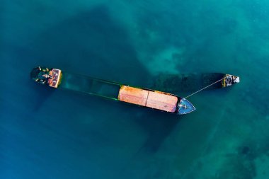 Deniz kenarında batık kargo gemisi veya römorkör havadan drone görünümü. Deniz suyu üzerinde gemi burun ile Gemi enkazı gemi