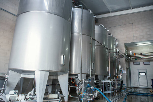 Stainless steel or metal juice factory equipment, large reservoirs or tanks and pipes in modern plat