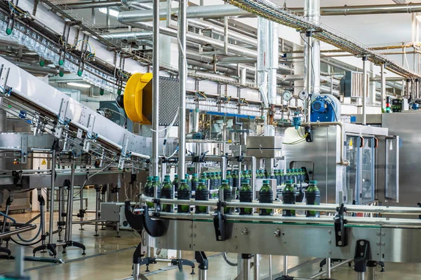 Cinta transportadora o línea en planta de bebidas con modernos equipos de máquinas industriales automatizadas. Botellas de plástico PET en interior de fábrica —  Fotos de Stock