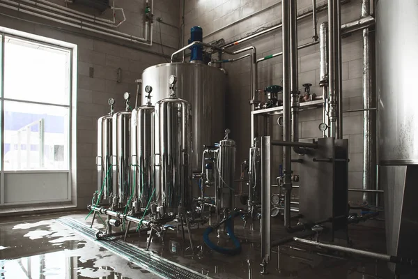 Grandes depósitos y tanques y tuberías con manómetros en la moderna planta de producción de jugo y agua. Fondo interior industrial —  Fotos de Stock