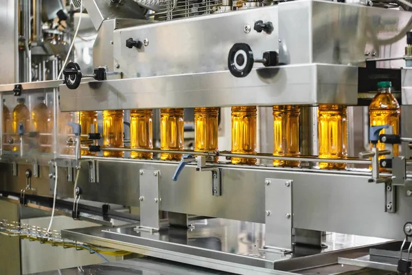 Botellas con jugo orgánico fresco o aceite de girasol en cinta transportadora automática en el interior de la fábrica con equipos modernos de máquinas industriales — Foto de Stock