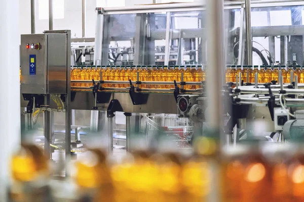 Botellas con jugo orgánico fresco o aceite de girasol en cinta transportadora automática en el interior de la fábrica con equipos modernos de máquinas industriales — Foto de Stock