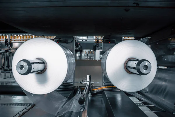 Rollo de plástico en la máquina de envasado de alimentos industriales herramienta en taller de fábrica — Foto de Stock