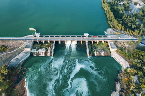 Воздушный панорамный вид на бетонную плотину на водохранилище с текущей водой, гидроэлектростанцию, дронный выстрел — стоковое фото