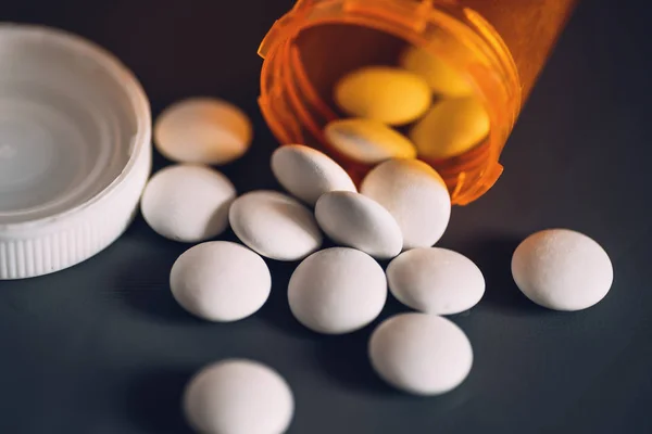 Λευκά χάπια και πορτοκαλί μπουκάλι χάπι σε γκρίζο τραπέζι, στιγμιότυπο. Έννοια της φαρμακευτικής αγωγής — Φωτογραφία Αρχείου