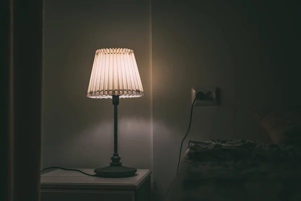 Bedroom lamp on night table in hotel room at night — Stock Photo, Image