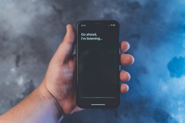 Moskova, Rusya - Circa Ağustos 2019 : Erkek elinde Iphone Xr ve sesli Apple dijital asistanı Siri ve akıllı telefon ekranında metin tarafından aktive: Devam edin, dinliyorum..