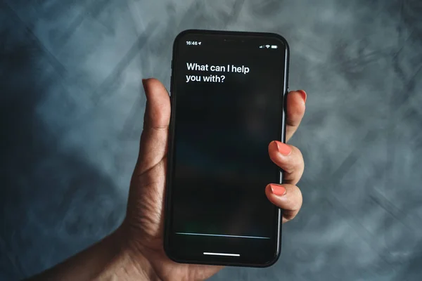 Moscou, Russie - Vers août 2019 : Siri - Assistant vocal Apple activé par la voix à la main féminine et le texte à l'écran de l'iPhone : Que puis-je vous aider ? Mode vocal d'interaction avec le téléphone — Photo