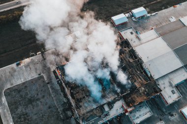 Yanan çatıdan büyük duman ile yanan sanayi binasının havadan görünümü, yangın felaket drone fotoğraf