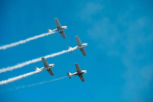 Airplanes with white smoke traces on air show. Pilots make tricks on jets at blue sky background Stock Image