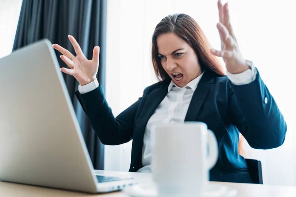 Stressed angry business woman screaming on laptop or notebook in office — Stock Photo, Image