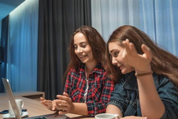 Dua wanita muda menarik di rumah dengan laptop, berbicara satu sama lain dan tertawa. Persahabatan atau konsep pasangan perempuan — Stok Foto