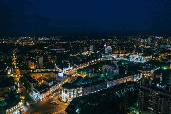 Vista aérea nocturna de la ciudad, volando por encima de un moderno edificio de vidrio iluminado con reflejos en el centro de Europa — Foto de Stock