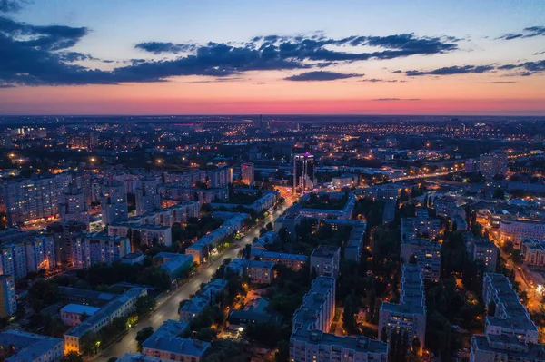 Vista aérea de la ciudad nocturna con carreteras iluminadas, tráfico de automóviles y diferentes edificios, tiro con drones — Foto de Stock