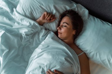 Genç güzel kız veya kadın gece büyük yatakta yalnız uyku, üst görünümü