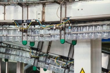 Pet plastik şişeler su fabrikasında veya fabrika üretiminde otomatik konveyör hattı veya bandı üzerinde hareket, yakın
