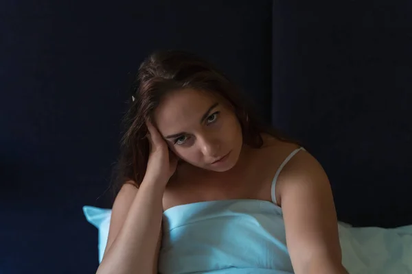 Stanco giovane ragazza seduta a letto e guarda fotocamera, insonnia, stress e disturbi del sonno concetto — Foto Stock