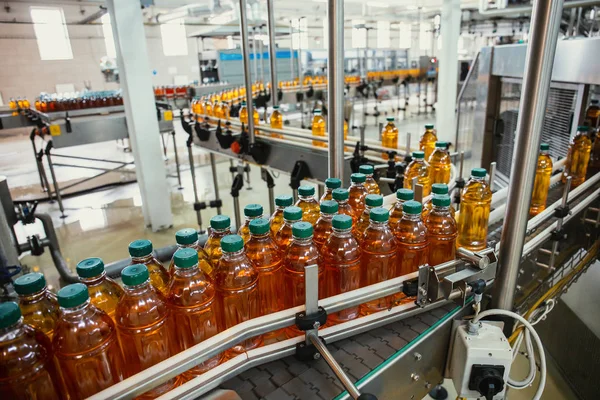 現代の工場設備のジュースのペットボトルが付いているコンベヤーライン。飲料製造工場内部内部 — ストック写真