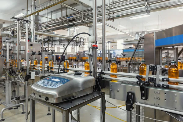 Botellas de plástico con jugo en la línea transportadora automatizada o en la banda en la moderna planta de bebidas o producción en fábrica —  Fotos de Stock