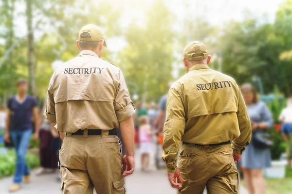 Due guardie di sicurezza maschili su evento pubblico tra sfondo sfocato di molte persone sulla strada soleggiata — Foto Stock