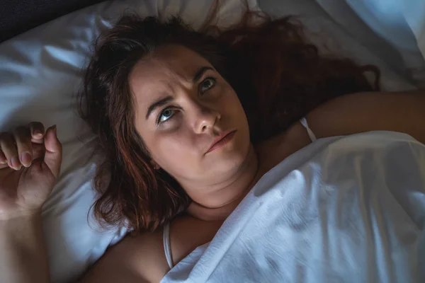 Young stressed or depressed woman lies in bed, can not sleep. Insomnia concept, top view — Stock Photo, Image