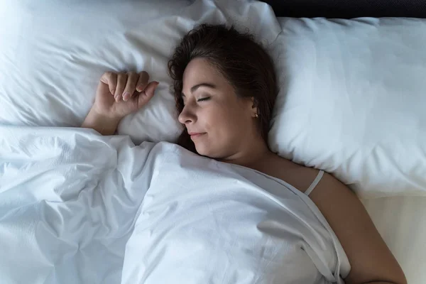 Ung vacker flicka eller kvinna sover ensam i stor säng, uppifrån — Stockfoto