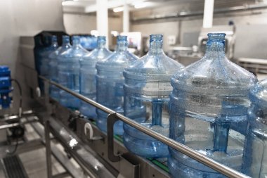 Su fabrikası. Otomatik konveyör hattında yıkandıktan ve temizlendikten sonra plastik şişe veya galon