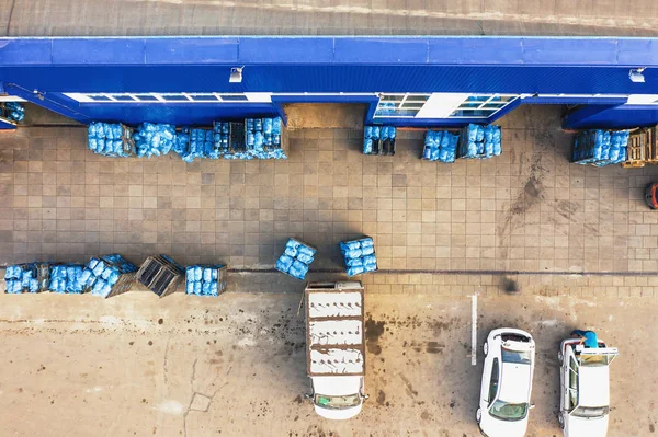 Аерофотозйомка вантажного складу заводу питної води або заводу, стелажі з пластиковими пляшками або галонами, готові до завантаження на вантажівках — стокове фото