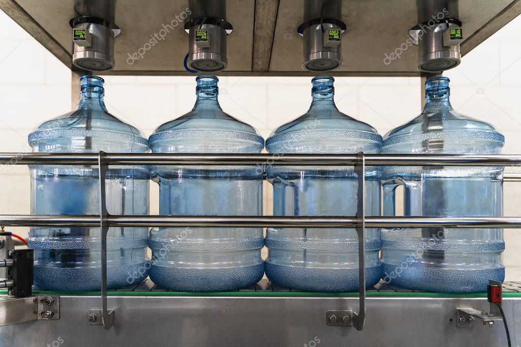Automatic integrity check of plastic bottles or gallons under pressure at purified drinking water plant or factory, close up