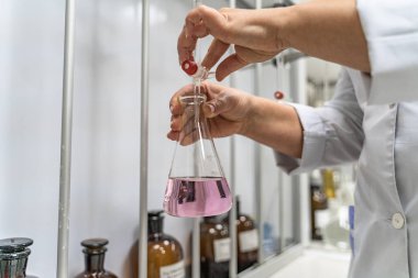 Laboratuvar kabı testte, kimyasal reaksiyon. Laboratuvar çalışanı saflaştırılmış içme suyunu kirler için kontrol ediyor