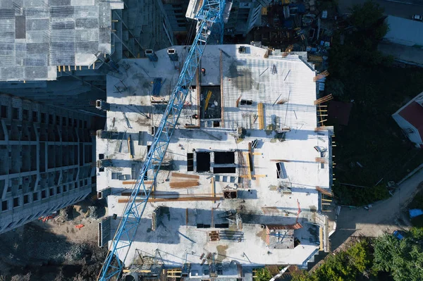 Вид сверху на строительную площадку современных бетонных зданий с промышленным оборудованием, кранами, рабочими. Фотография дрона — стоковое фото