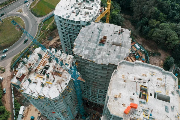 Вид сверху на строительную площадку современных бетонных зданий с промышленным оборудованием, кранами, рабочими. Фотография дрона — стоковое фото