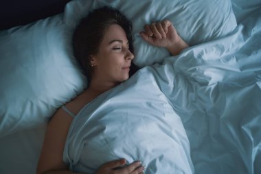 Genç güzel kız veya kadın gece büyük yatakta yalnız uyku, üst görünümü