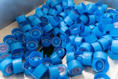 Fabrikada su ile şişeler için mavi plastik kapaklar, yakın