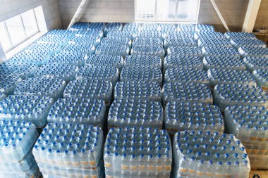 Saf su ve mavi kapaklar içme ile birçok plastik şişe. Fabrika ambarındaki veya depodaki süpermarketlere teslime hazır mallar