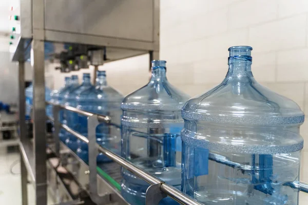 純水製造工場のコンベアベルト機械設備の空のペットボトルまたはガロン — ストック写真