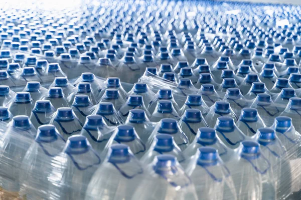 Muchas botellas de plástico con agua potable y tapas azules — Foto de Stock