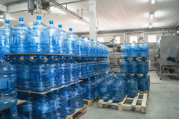 Gallons or plastic bottles of purified drinking water on pallets in factory interior inside