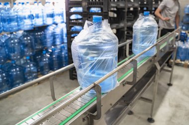 Selofan içinde paketlenmiş plastik şişelerde temiz saf içme suyu ile konveyör hattı veya kemer, su fabrikasında bitmiş mal yükleme