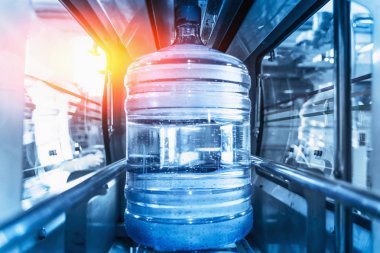 Plastik şişe veya otomatik konveyör üretim hattı içinde saflaştırılmış içme suyu galon. Su fabrikası, mavi güneş ışığı parlama ile tonda